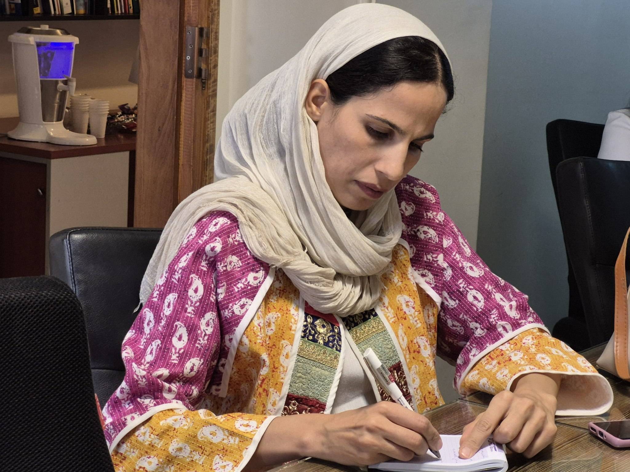 عکسی از یک زن در حال یادداشت‌برداری در کارگاه تولید بدون کارخانه، با دقت و تمرکز بر فرآیندهای تولید.